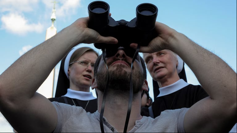 Dos monjas detrás de un hombre que utiliza binoculares para observar la chimenea de la Capilla Sixtina. (Foto: Reuters / Marko Djurica)