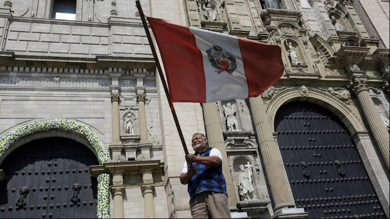 Un peruano hace flamear la bandera nacional frente a la Catedral de Lima (Foto: AP)